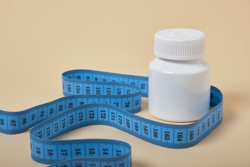 Vit medicinburk med måttband